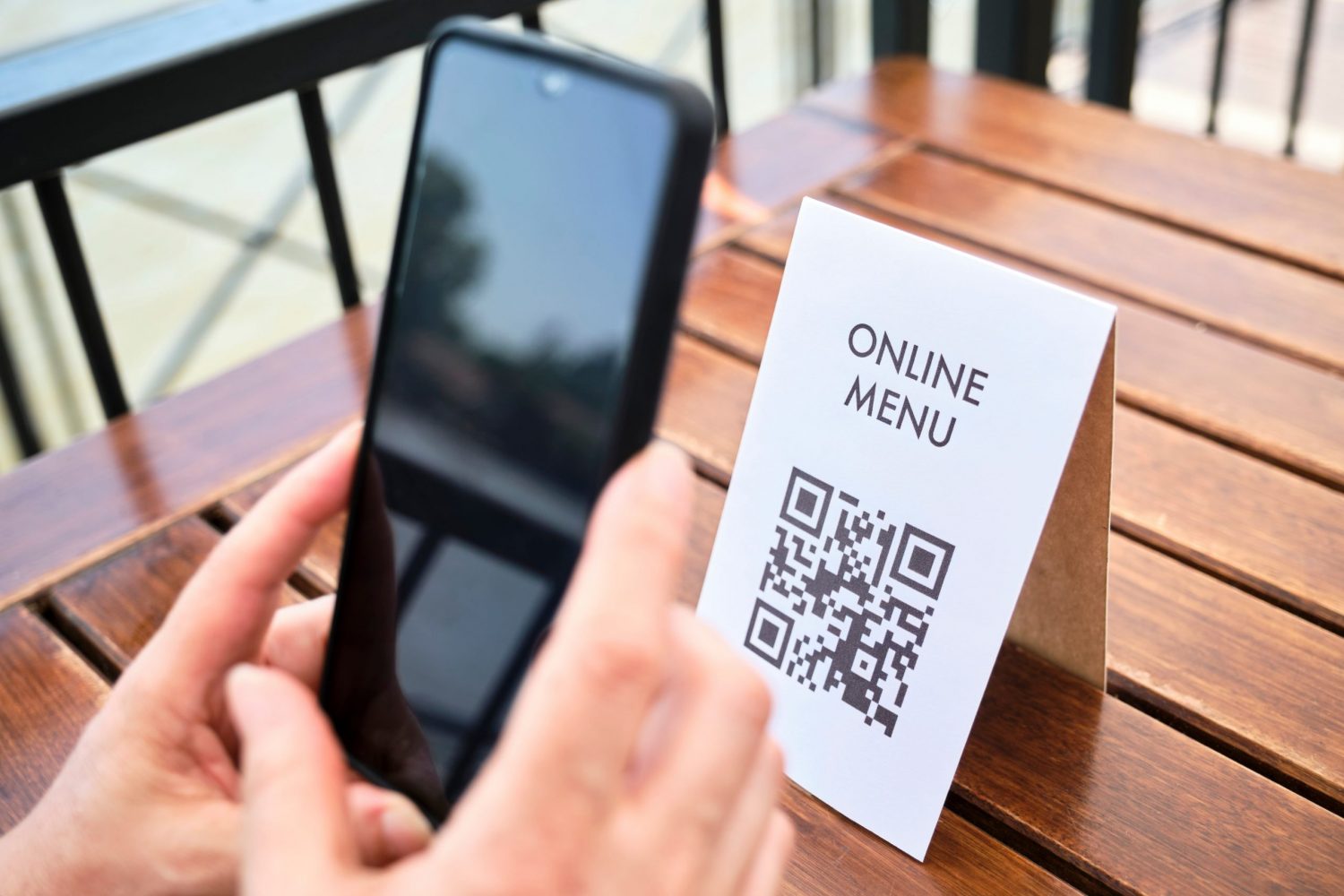 Hands of an unrecognizable woman scanning a QR code with a smartphone to access a restaurant menu; use of contactless technology in everyday life.